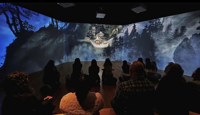 Visitors sitting in a room with large scale immersive projection